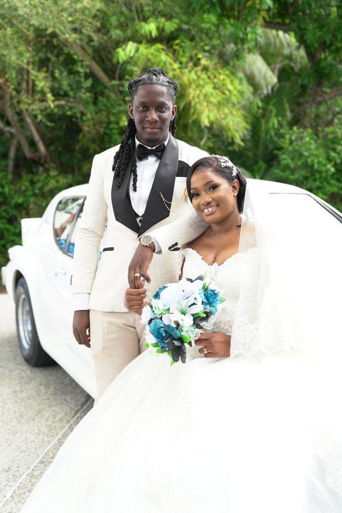 Newlyweds posing beside a vintage white wedding car