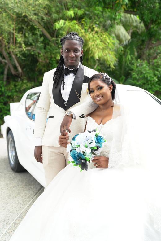Newlyweds posing beside a vintage white wedding car